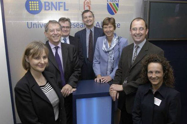 Image is of seven people smiling for a photograph in front of the Manchester University, UMIST and BNFL logos at the BNFL endowment award